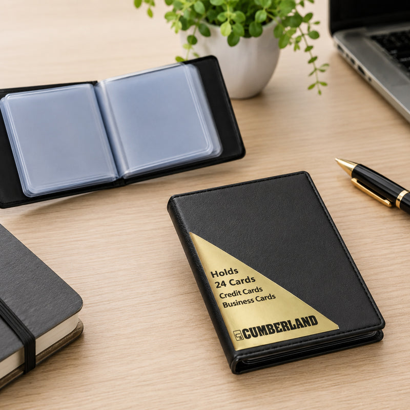 Closed Cumberland Business Card File with a second file opened in the background on a modern workspace featuring a notebook, laptop, pen and indoor plant, illustrating compact storage and organised card management.