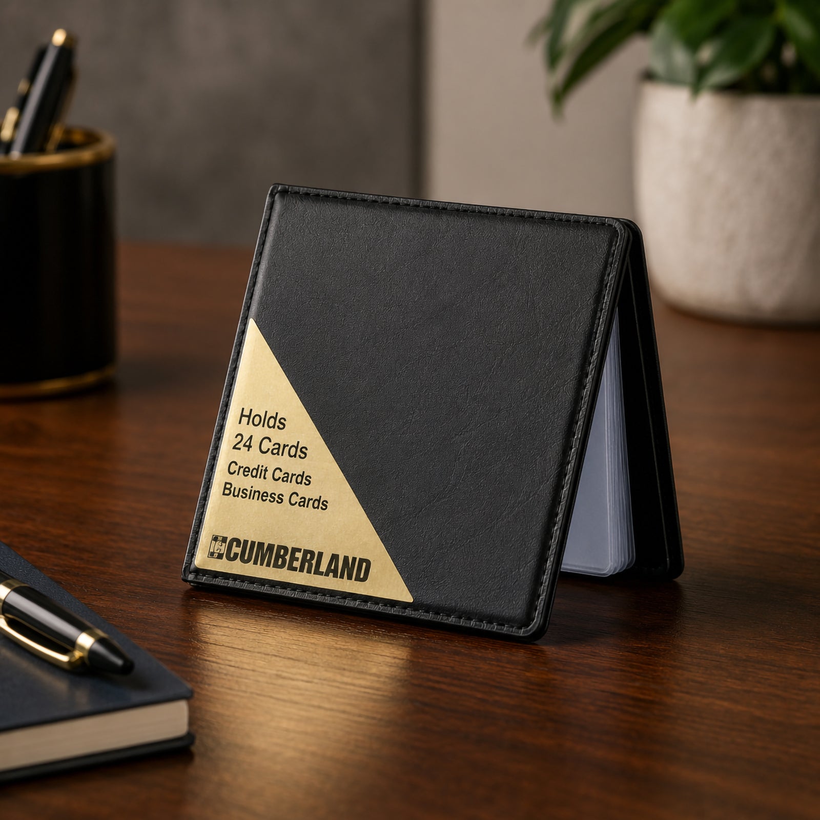 Cumberland Business Card File standing partially open on a premium timber executive desk, highlighting the black PVC leathergrain cover, elegant gold corner detail and compact design suitable for professional office environments.
