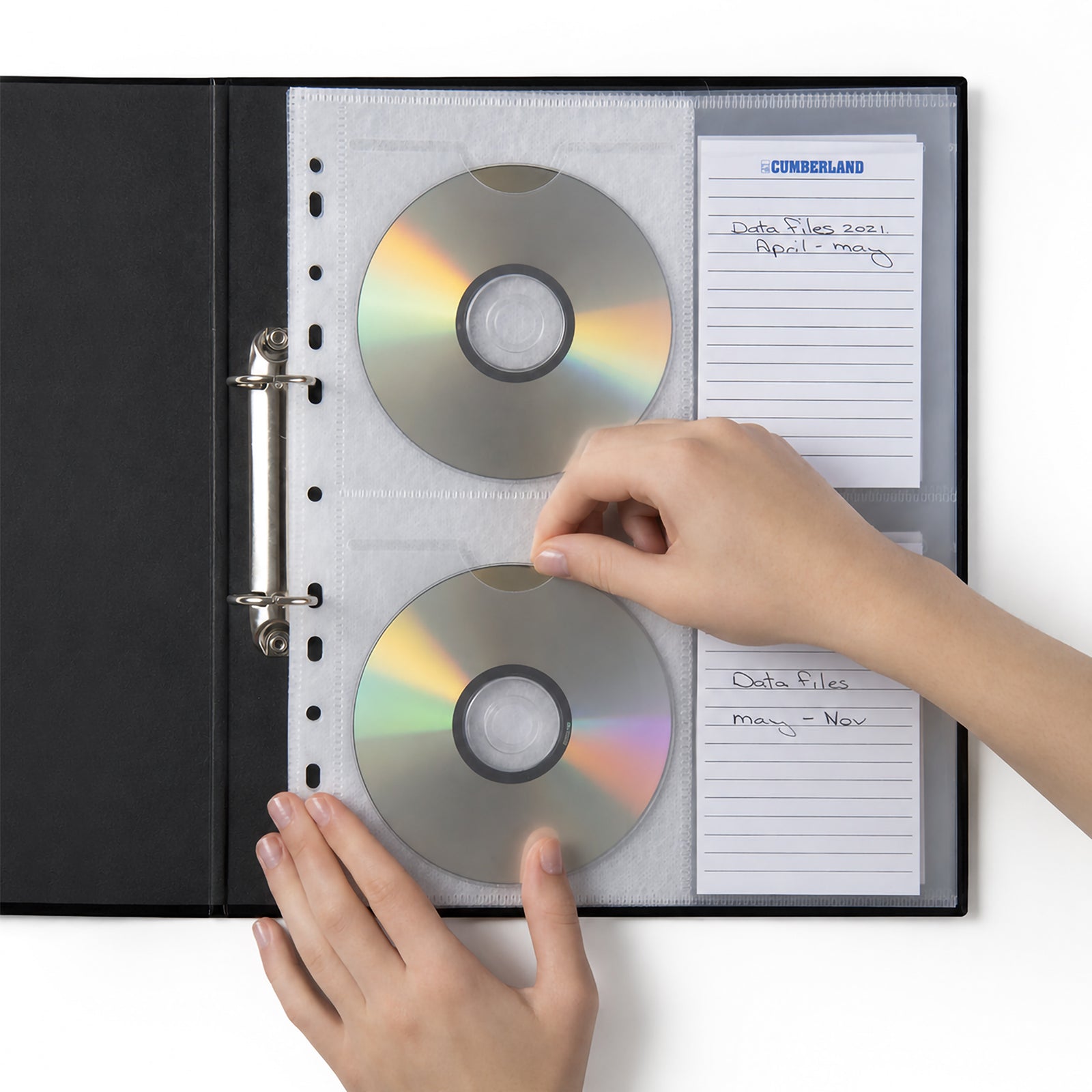 Close up of hands inserting and removing compact discs from a Cumberland binder pocket while labelled index cards identify archived files inside an A4 ring binder for efficient document and media organisation.