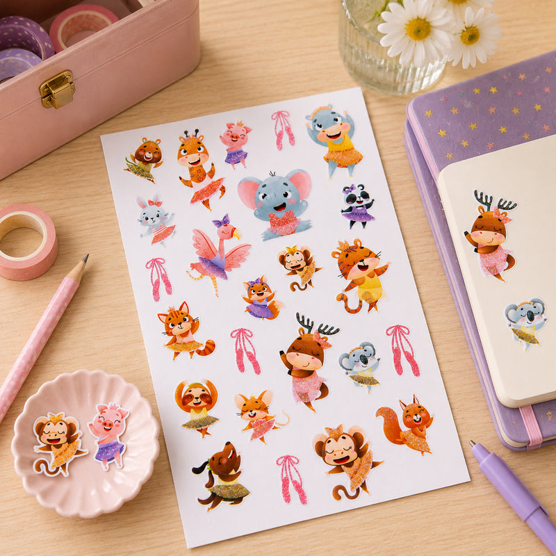 Dancing Dreamers sticker sheet displayed with notebooks, stationery and decorative craft supplies. Glitter accented animals including elephants, foxes, koalas and deer appear in joyful dance poses.