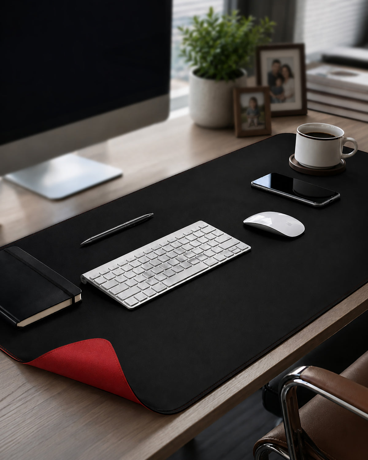 Deflecto faux-leather desk mat 800 x 400mm on an office desk under a keyboard and mouse, black side up with the red side showing at one corner