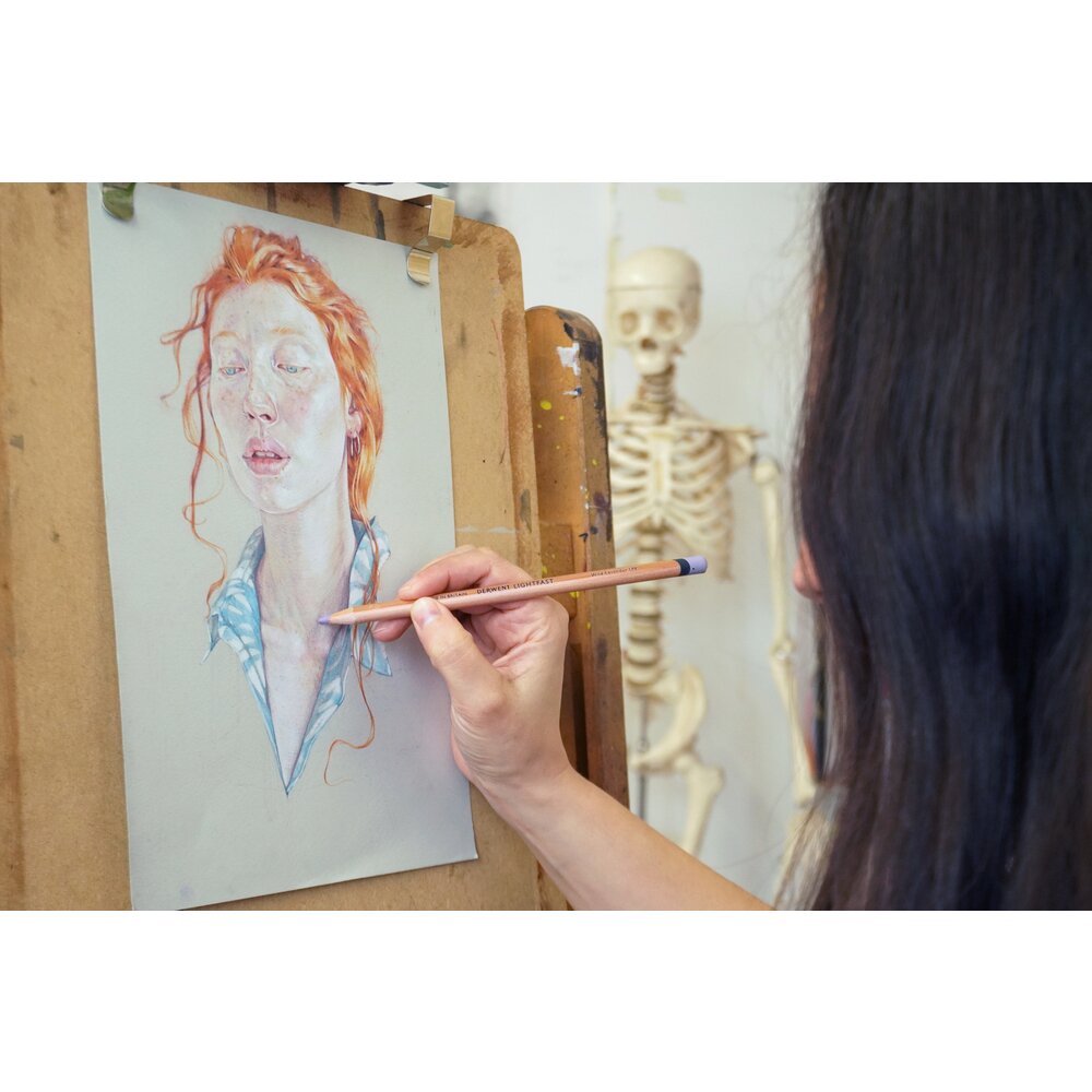 Artist working on a coloured pencil portrait at an easel with a Derwent Lightfast pencil, a Derwent range image showing the pencils in use