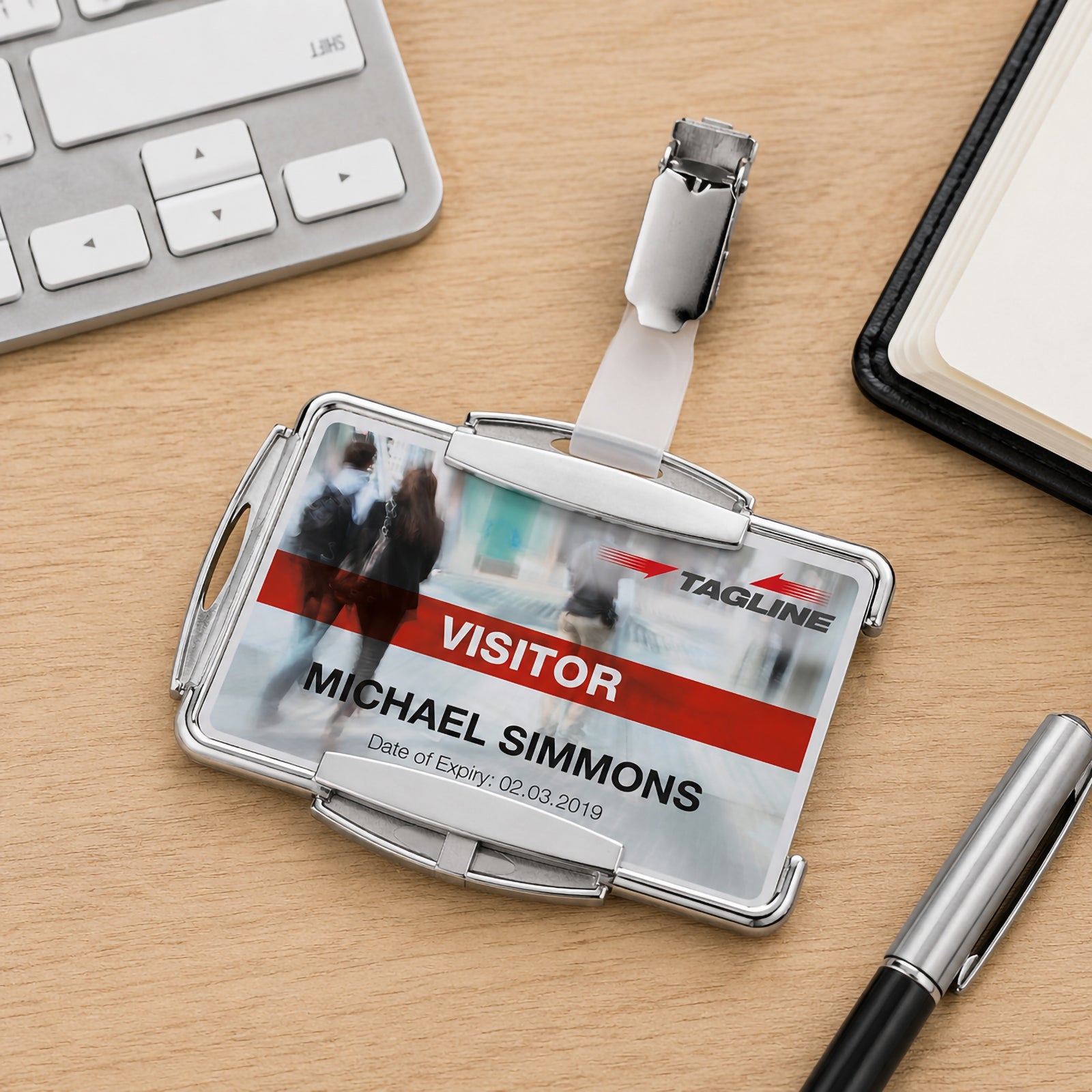 The Durable RFID Secure Mono Card Holder displayed on a clean wooden office desk beside a keyboard, notebook and premium pen. The close up showcases the RFID secure holder, rotating clip fastener and durable construction suitable for everyday business and workplace identification.