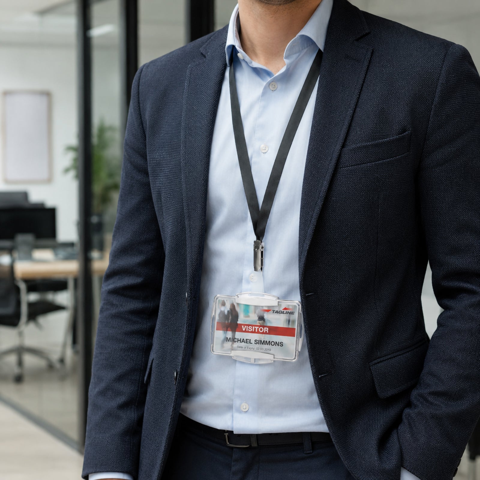 Professional wearing the Durable RFID Secure Mono Card Holder attached to a black lanyard in a modern office environment. The silver framed holder clearly displays a visitor identification card while demonstrating comfortable everyday wear and secure presentation for professional workplaces.