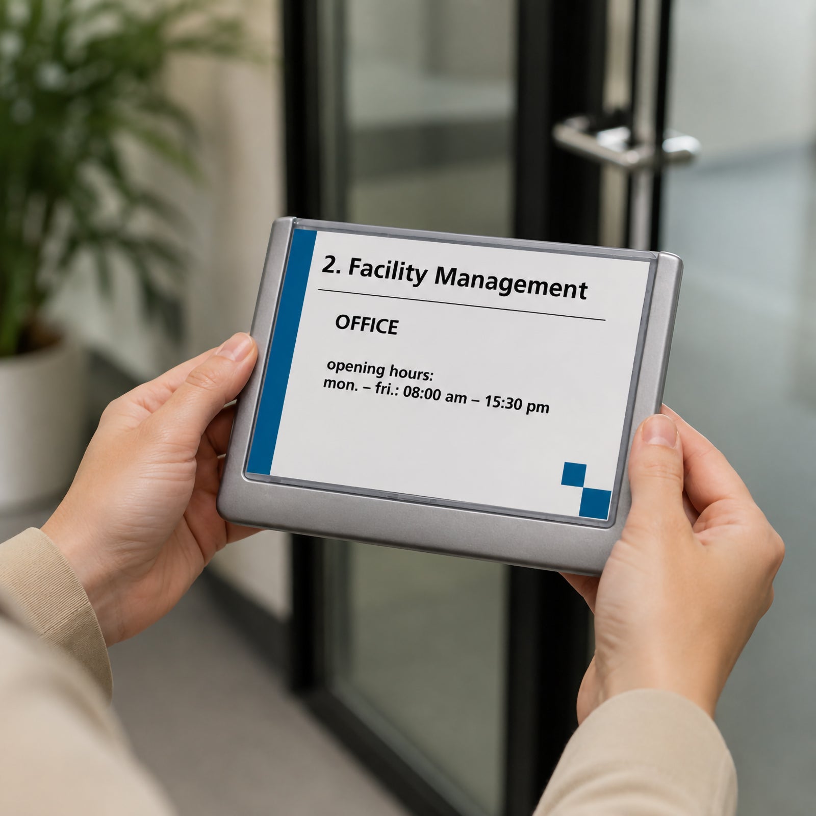 Hands holding the Durable Click Sign 149 x 105.5mm Grey in front of a modern office entrance, demonstrating the portable sign before installation. The grey framed sign features a removable insert displaying office information, highlighting its professional appearance and easy insert exchange design for commercial workplaces.