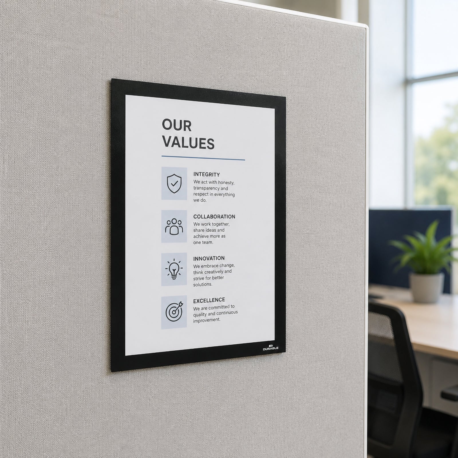 The Durable DURAFRAME Grip Textile Surface A4 Black mounted on a textile office partition displaying company values in a bright modern workspace. The image highlights its suitability for presenting important workplace information on fabric covered surfaces.