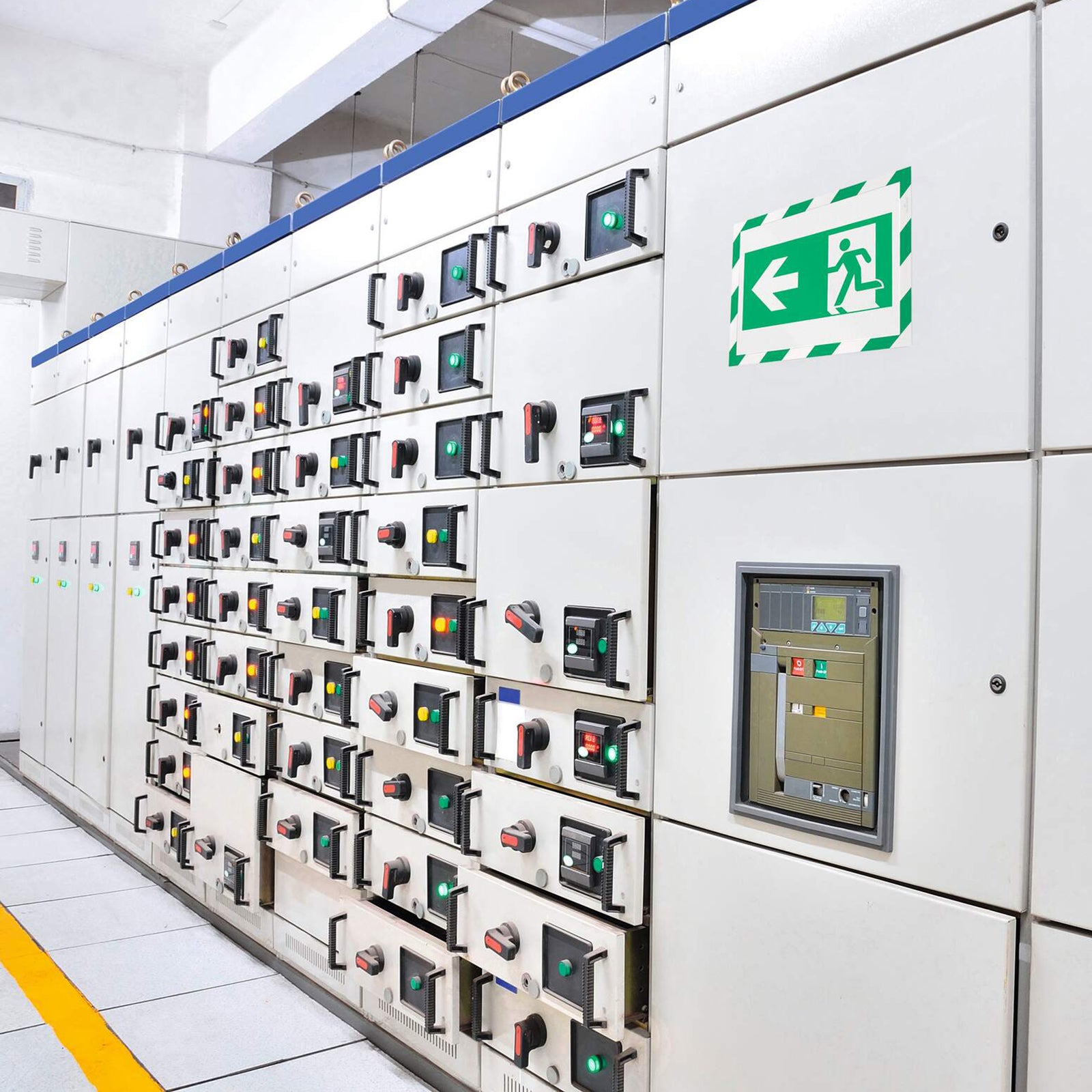 Durable DURAFRAME Magnetic Security A4 Green White frame mounted on an industrial electrical control cabinet displaying an emergency exit direction sign. The magnetic frame provides a professional and highly visible safety display in technical environments.
