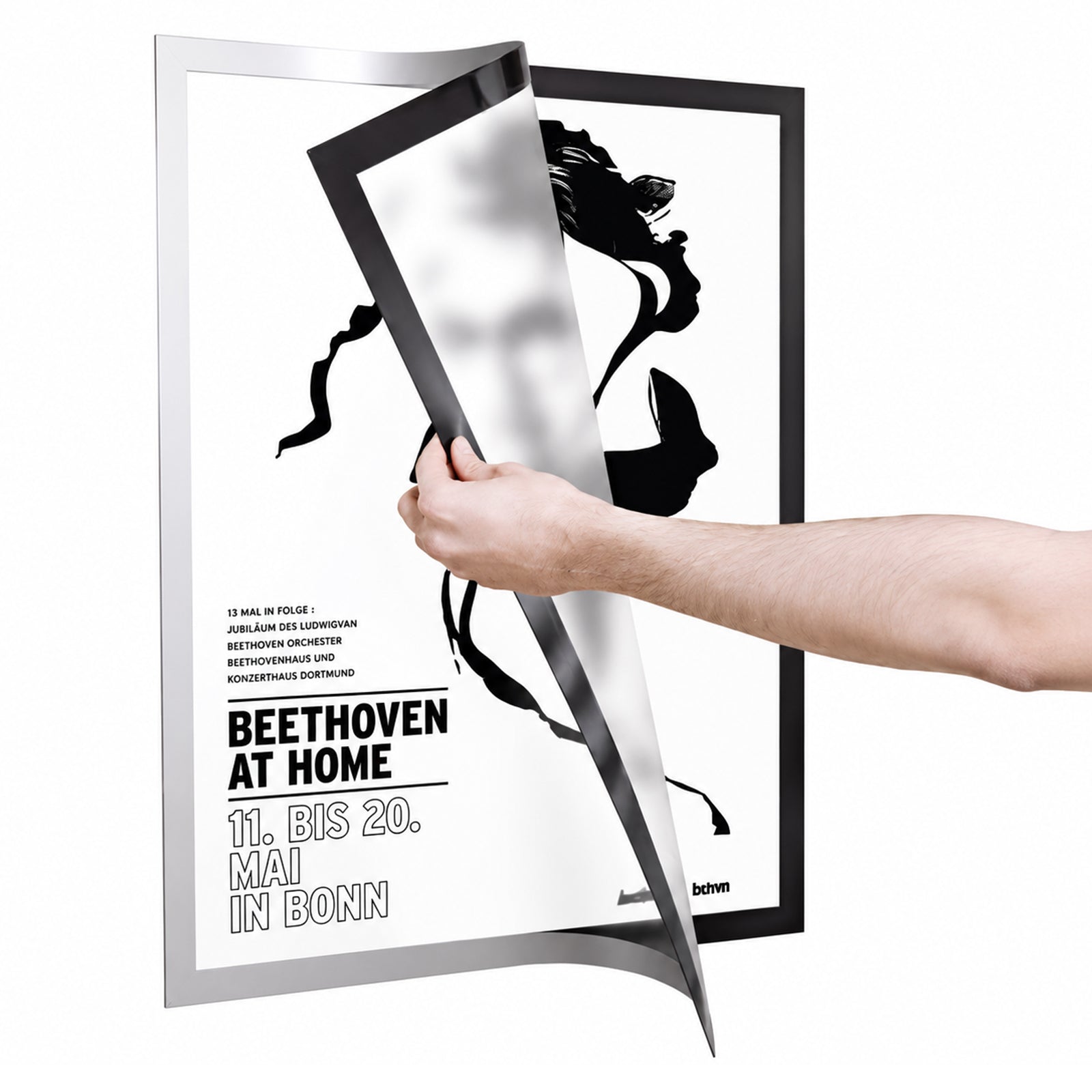 Close up of a user lifting the magnetic silver border of the Durable DURAFRAME Poster A2 to replace a poster. The flexible magnetic frame opens easily while remaining attached to the wall, demonstrating fast and convenient document changes.