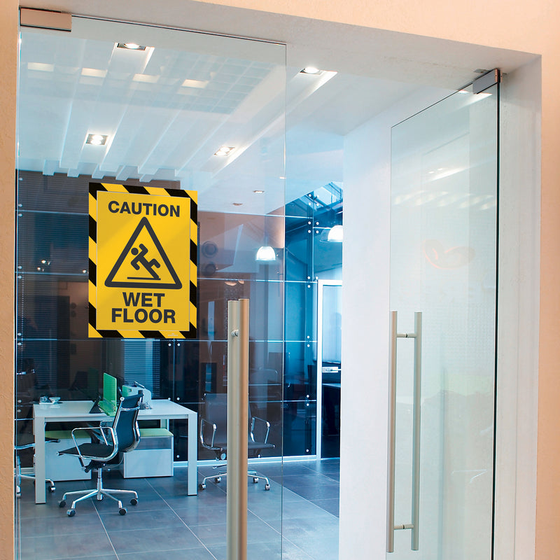 Durable DURAFRAME Security A4 Yellow Black installed on a modern office glass door displaying a wet floor warning. The professional safety frame provides high visibility while maintaining a clean workplace appearance.