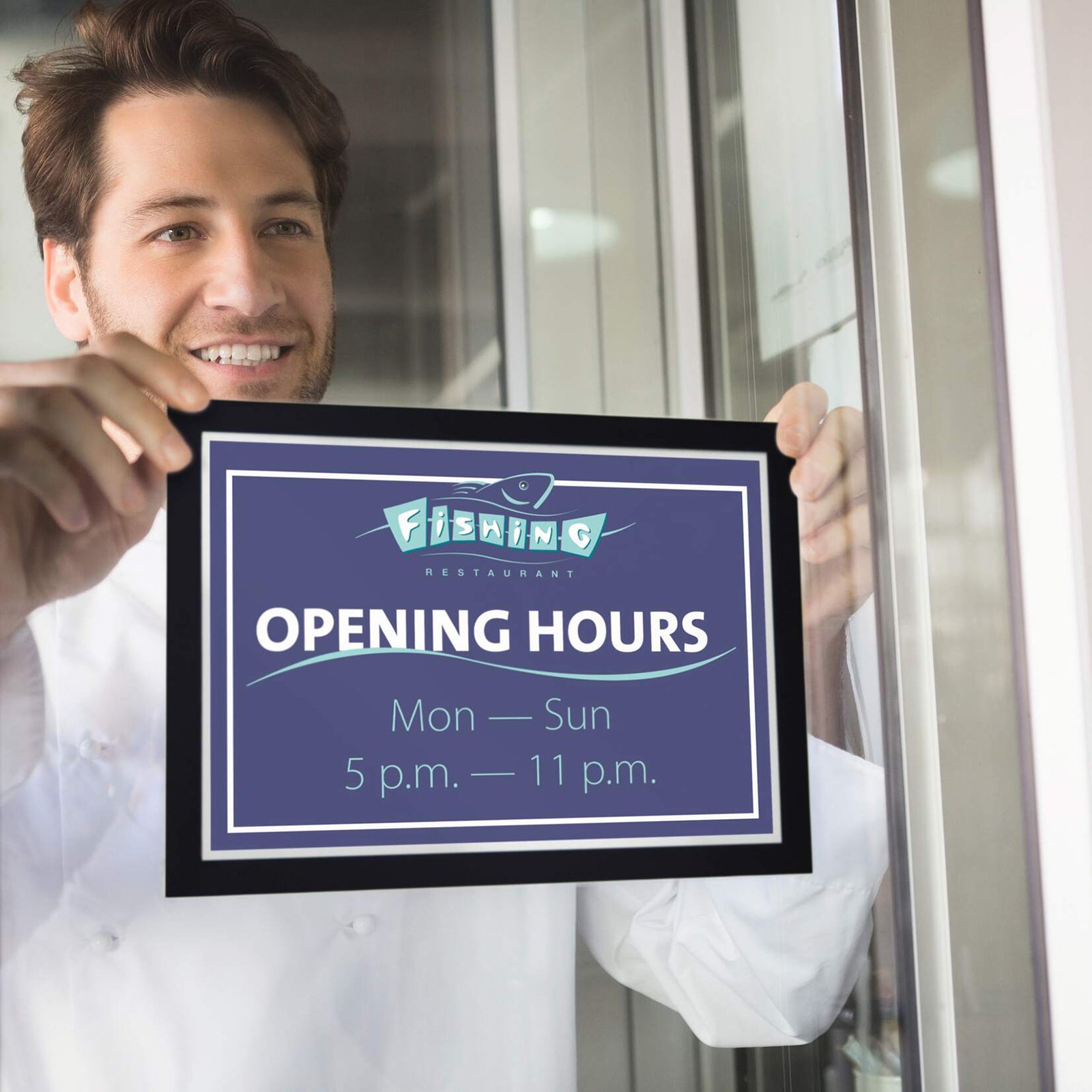 Restaurant staff member positioning the Durable DURAFRAME Sun A4 Black on an internal glass window to display opening hours. The premium black frame creates a bold, professional presentation while the static cling design allows simple positioning without adhesive.