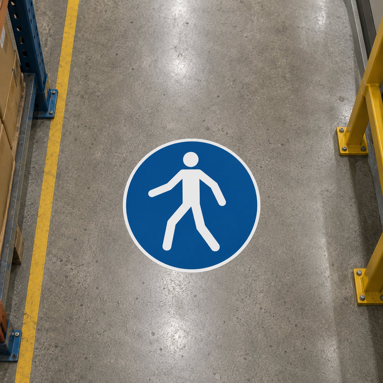 Overhead view of the Durable Floor Marking Sign Use Walkway 430mm Blue installed on a warehouse floor between storage racking, clearly identifying the designated pedestrian pathway through an industrial workplace.