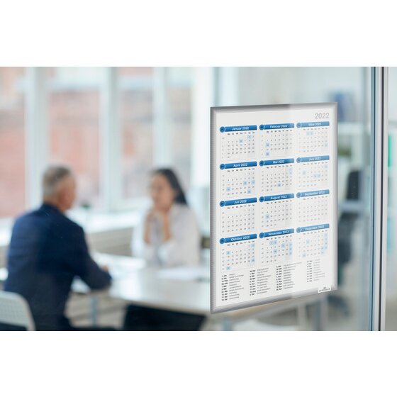 Grey Duraframe Info Frame holding a year calendar on a glass partition beside a meeting table