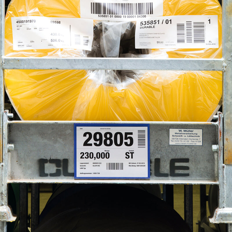 A Durable A5 Landscape Magnetic Document Pouch is attached to the front of a metal industrial container holding large packaged materials. The pouch prominently displays warehouse identification and logistics documentation for efficient inventory management.
