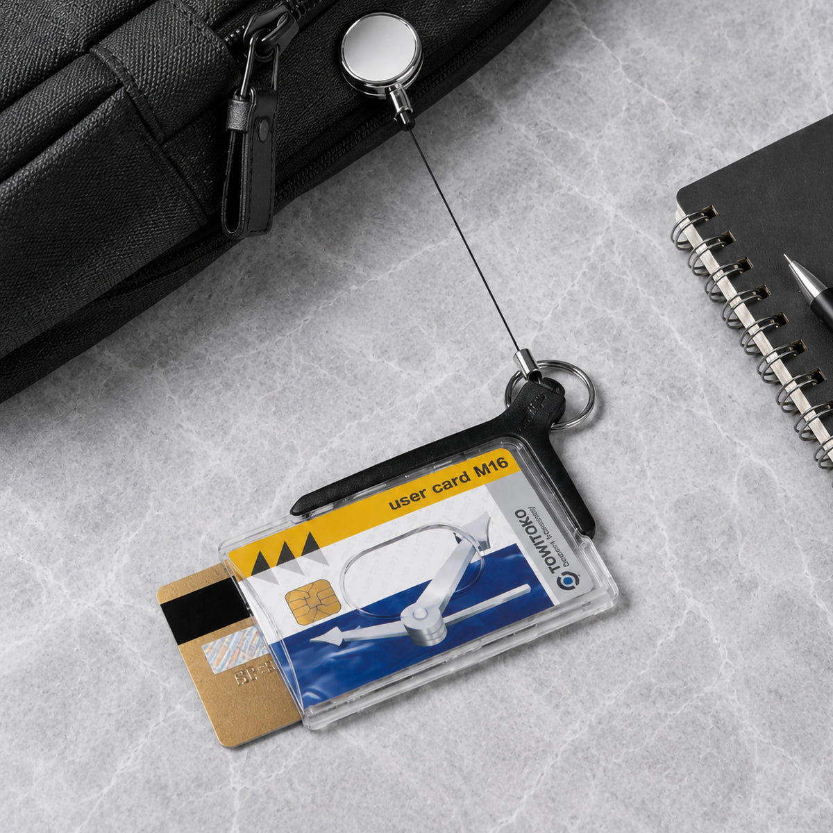 Deluxe Pro Duo card holder with two cards on a grey stone desk beside a notebook and black bag