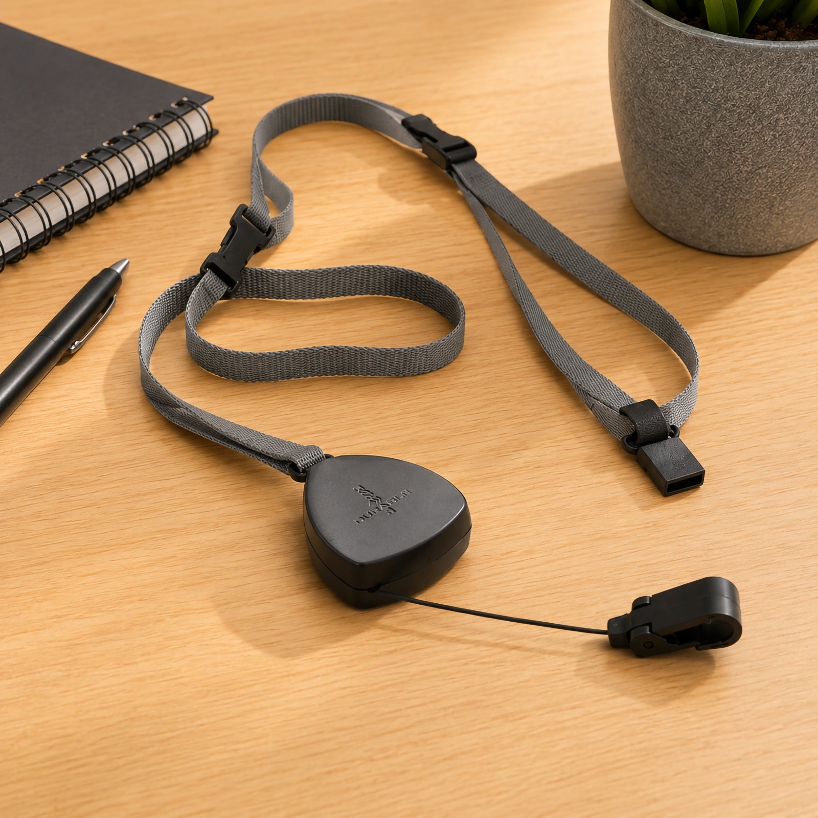 Close up of the Durable Textile Lanyard Flex displayed on a tidy office desk beside a notebook, pen and indoor plant. The retractable badge reel, adjustable textile strap and snap hook highlight the product's premium construction and professional design.