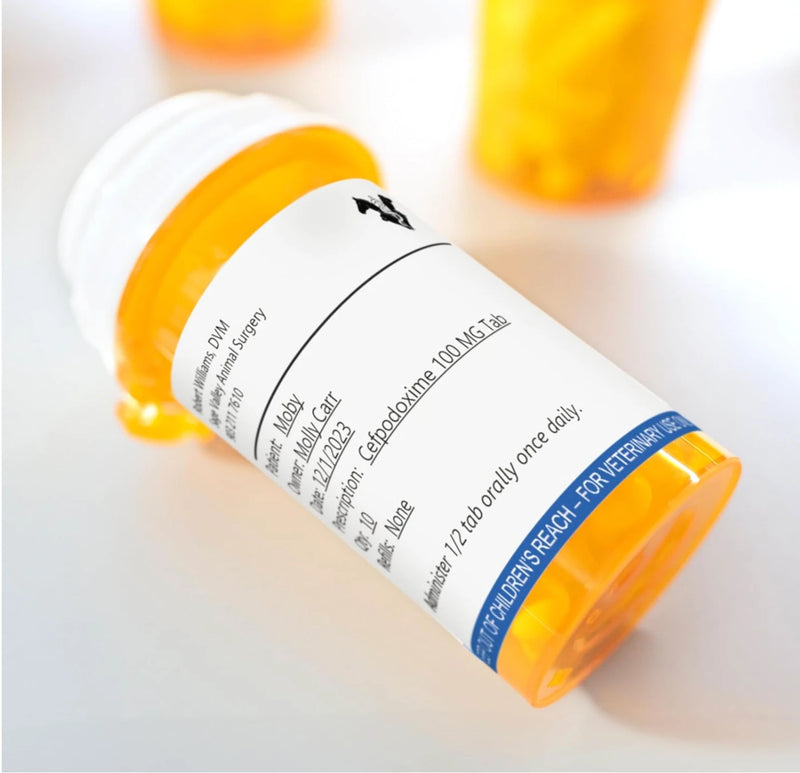 Close up of a dispensing bottle with a completed Dymo veterinary label showing dosage directions beneath the printed caution strip.
