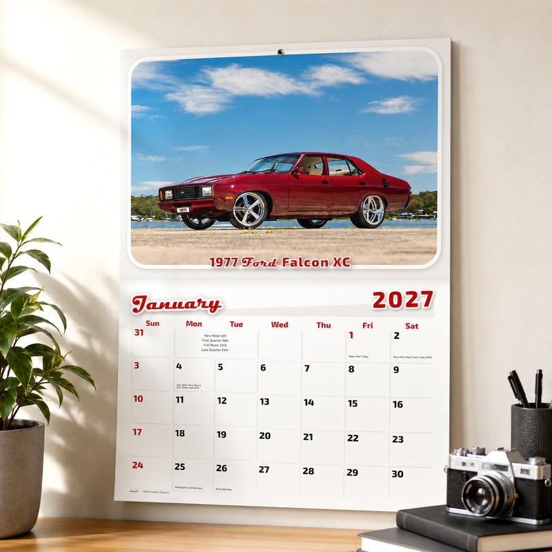 Easy2C Calendar 2027 Stitched Custom Classics A4 displayed above a timber desk in a stylish office. The January page features a restored red 1977 Ford Falcon XC with a large monthly planning layout and natural sunlight highlighting the calendar.