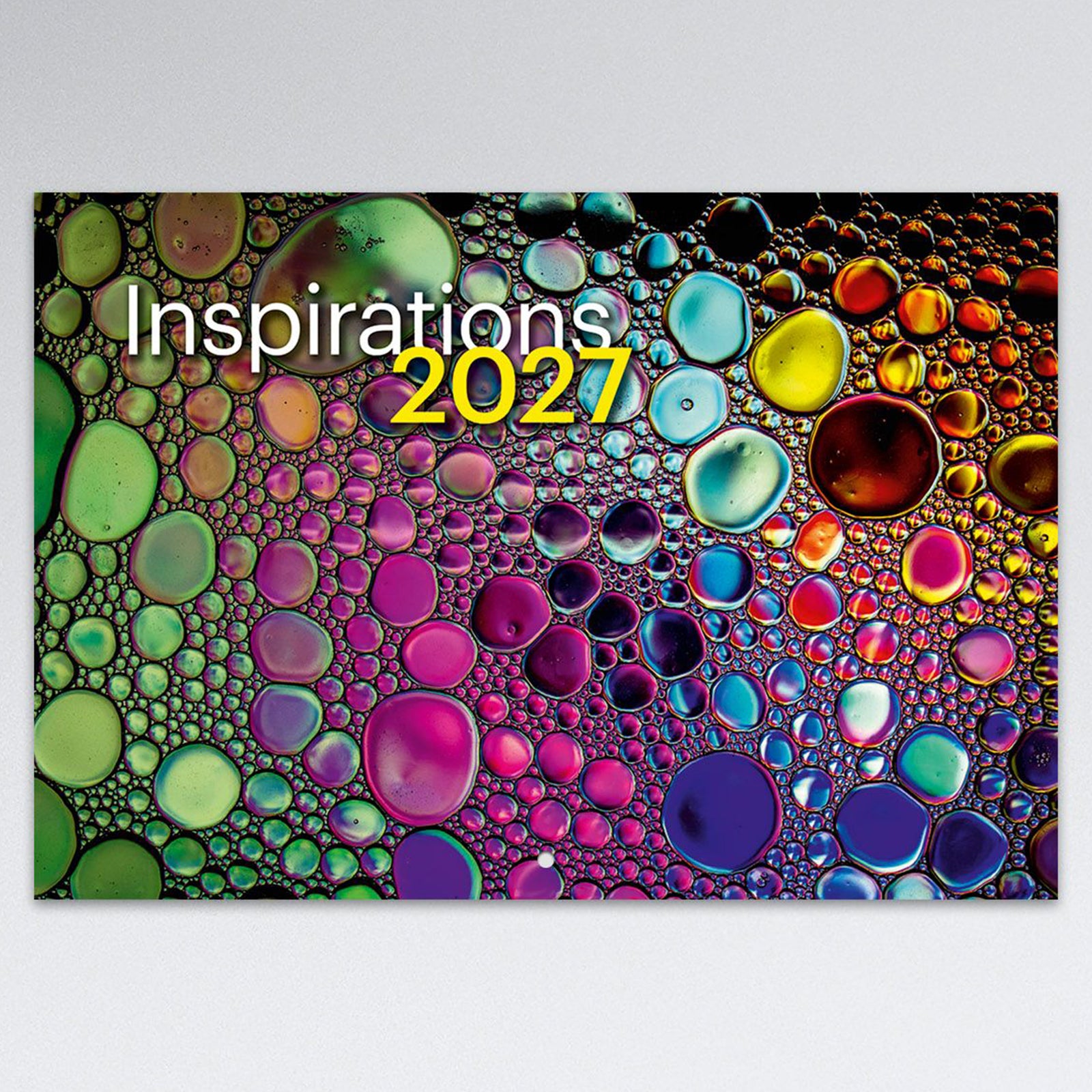 Front cover artwork of the Easy2C Inspirations 2027 stitched calendar featuring colourful abstract liquid bubble patterns and bold typography. The modern cover creates an eye catching presentation suitable for home or office display.