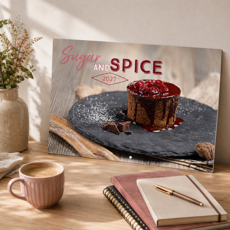 Front cover of the Easy2C Sugar and Spice 2027 stitched A4 calendar displayed on a timber desk beside a notebook and coffee. The cover features an elegant chocolate dessert with rich food styling and modern typography.
