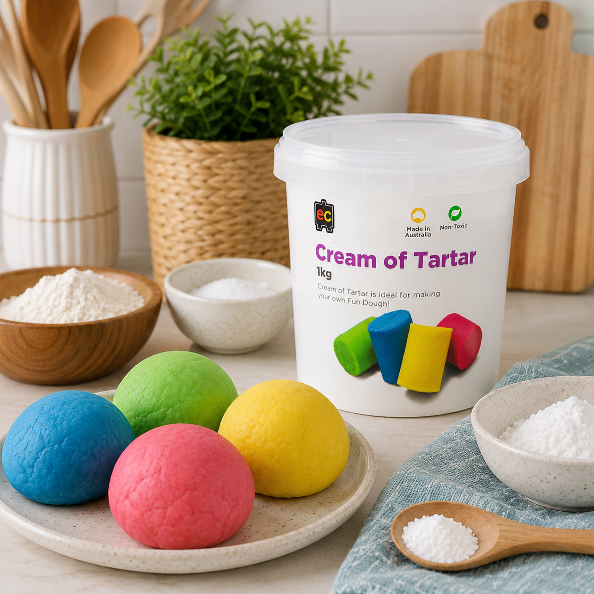 Educational Colours Cream of Tartar 1kg displayed in a bright kitchen craft setting beside blue, green, yellow and pink Fun Dough balls, with measured ingredients arranged nearby to demonstrate its use for homemade dough preparation.