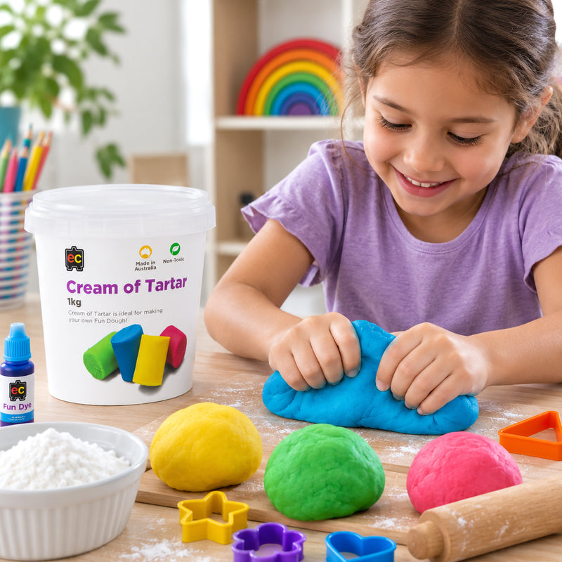 Educational Colours Cream of Tartar 1kg beside a child shaping bright blue homemade Fun Dough at a craft table, with colourful dough balls, cutters, rolling pin, flour and Educational Colours Fun Dye arranged for a creative activity.