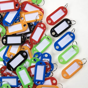 Pile of plastic key tags with split rings and white label windows in red, orange, blue, black and green