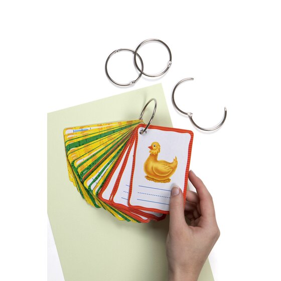 Hand holding a stack of picture flash cards with a duck on top, joined by a silver hinged ring