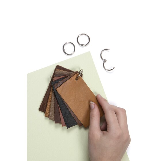 Hand holding a fan of brown and black leather swatches joined by a small silver hinged ring