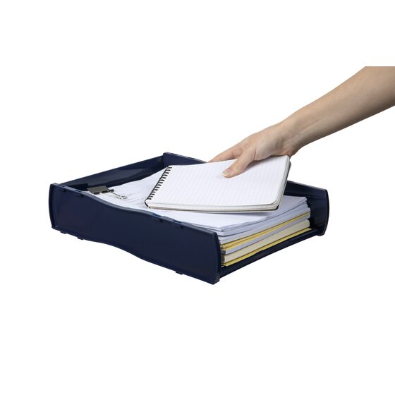 A hand setting a notebook on a paper stack inside the Blue Directors Nouveau tray