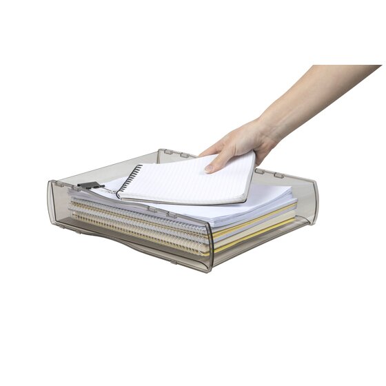 A hand placing a notebook on a stack of paper in the smoke tray, the paper outline visible through the tinted walls