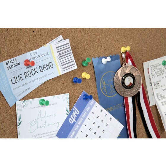 Coloured push pins holding tickets, an invitation, a calendar, a medal and receipts on a cork board