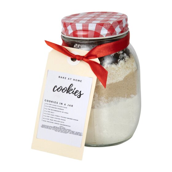 Buff tag printed Bake At Home Cookies with a cookies in a jar recipe, tied with red ribbon to a jar of layered ingredients