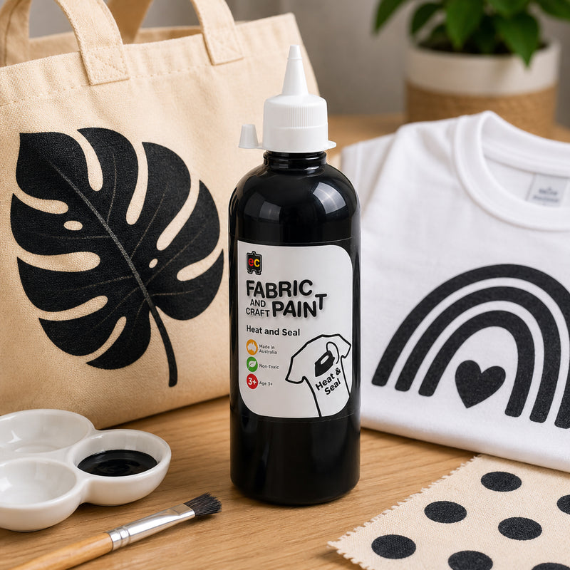 Educational Colours black fabric paint shown with a tote bag featuring bold tropical leaf artwork and a white shirt decorated with modern black rainbow graphics.