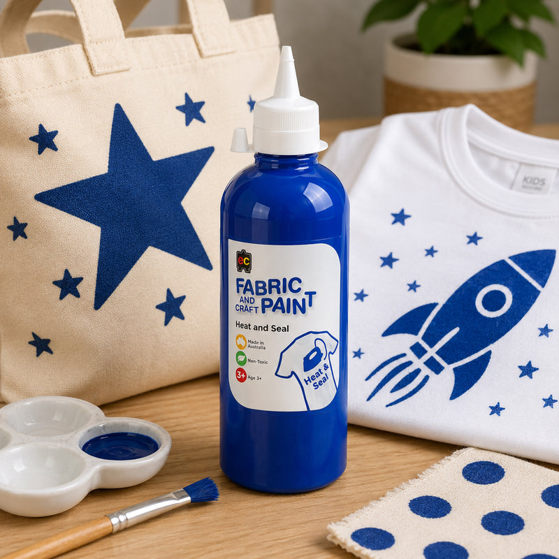 Educational Colours dark blue fabric paint shown beside a tote bag featuring blue star artwork and a white shirt decorated with rocket and space themed blue designs.