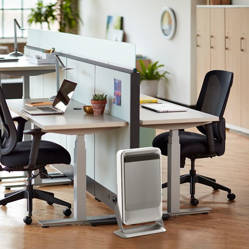 Office with sit stand desks and black chairs, an AeraMax Pro AM 2 purifier on its floor stand beside a desk