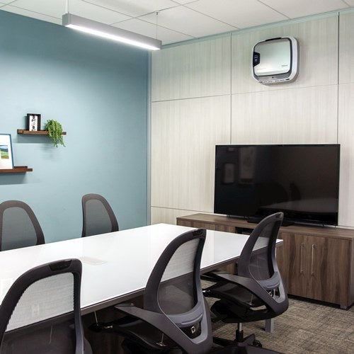 Meeting room with a white table, mesh chairs and a wall screen, an AM 3 PC purifier fixed high on the blue wall