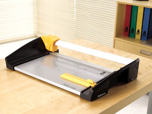 Atom A3 rotary trimmer on a wooden office desk in front of a shelf of coloured lever arch files