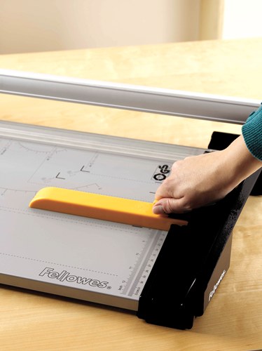 Hand setting the yellow paper clamp on the grey cutting base of a Fellowes Atom A3 trimmer