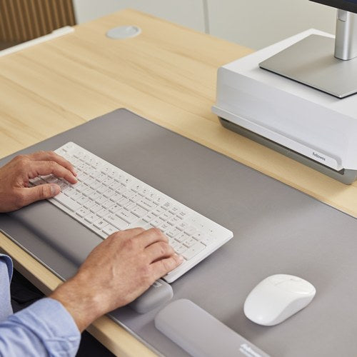 Typing on a white keyboard on a grey Breyta desk mat with grey Breyta wrist rests and a white mouse