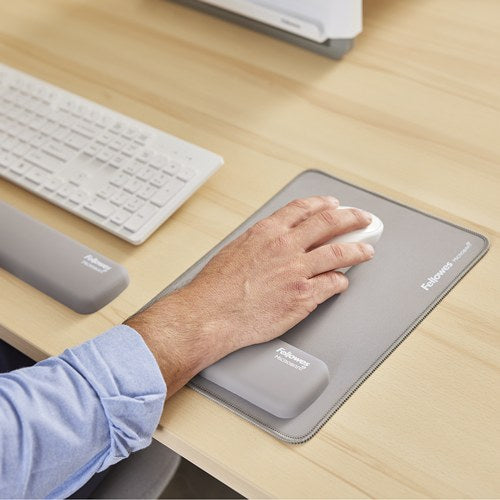 Hand on a white mouse on a grey Breyta XL mousepad with a grey palm rest beside a white keyboard