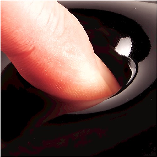 Close-up of a fingertip pressing down into glossy black gel, showing how the cushion gives way