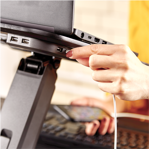Close-up of a hand plugging a white USB cable into a front charging port under the Hana laptop riser platform