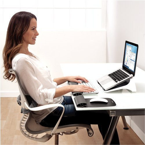 Woman typing on a separate keyboard at a white desk with her laptop raised on the I-Spire laptop lift