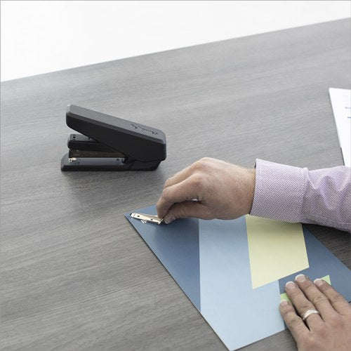 Hand using the detachable remover from a black LX850 to lift a staple from documents on a desk