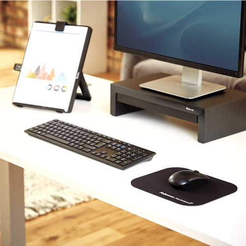 Black Fellowes Microban pad and mouse on a white desk next to a keyboard, monitor riser and copyholder