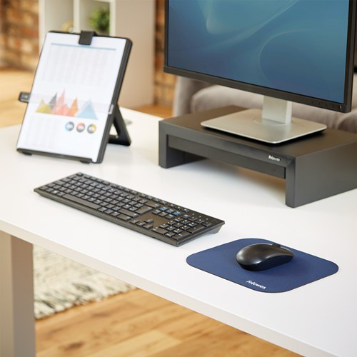 Blue Fellowes pad with a black mouse on a white office desk beside a keyboard and monitor riser