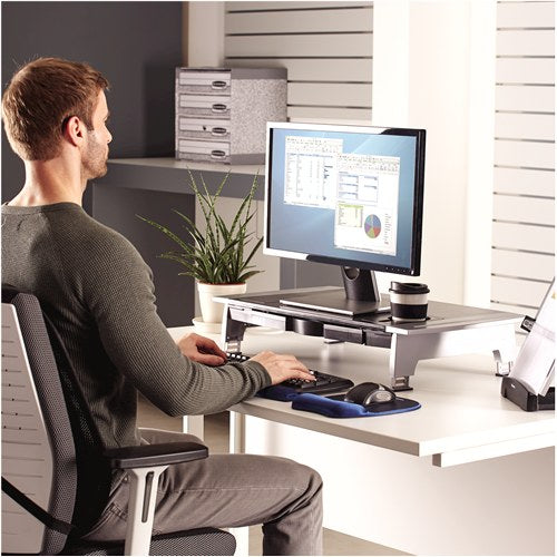 Man working at a desk with his monitor on the Office Suites premium riser and a keyboard in front