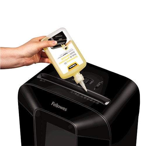 Hand squeezing Fellowes shredder oil from the nozzle along the paper entry of a black Fellowes shredder