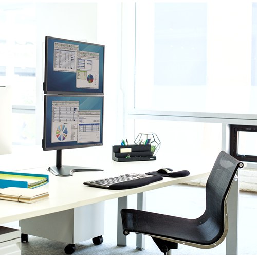 Two stacked screens on a Fellowes freestanding arm on a white desk by a window with an office chair