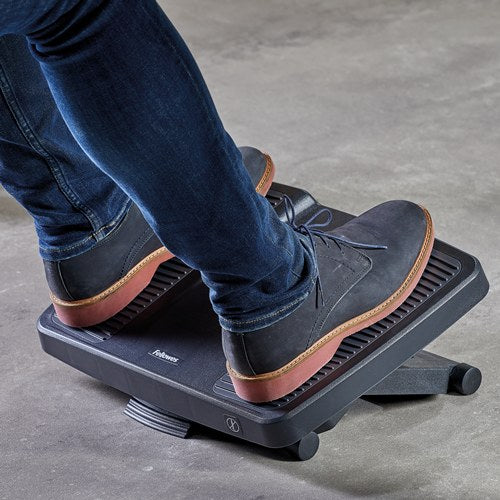 Man in jeans and boots with both feet on the Ultimate foot support on a grey concrete floor